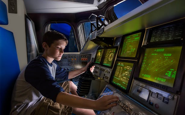 Child operating space shuttle simulator at Kennedy Space Centre.