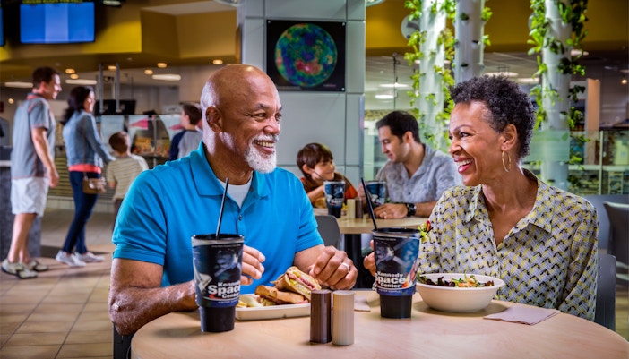 Couple dining at Kennedy Space Center café with space-themed decor.