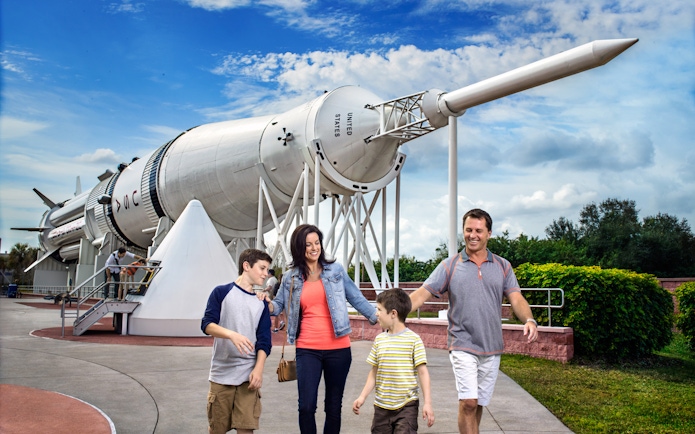 Family walking near Saturn V rocket at Kennedy Space Center.