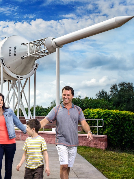 Family walking near Saturn V rocket at Kennedy Space Center.