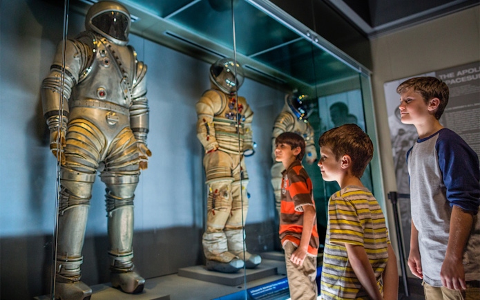 Children viewing astronaut suits at Kennedy Space Center exhibit.
