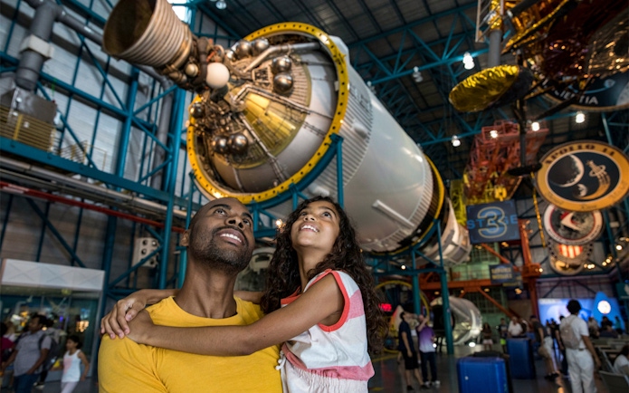 Father and daughter admiring a Saturn V rocket at Kennedy Space Center.