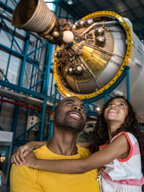 Father and daughter admiring a Saturn V rocket at Kennedy Space Center.