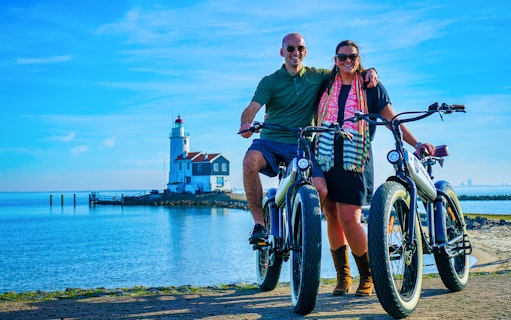 Couple on e-fatbikes near Volendam lighthouse, Amsterdam countryside.