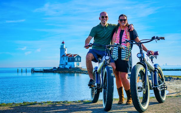 Couple on e-fatbikes near Volendam lighthouse, Amsterdam countryside.