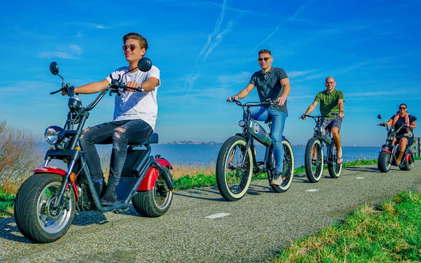Group riding e-scooters along a scenic path in Volendam, Amsterdam countryside.