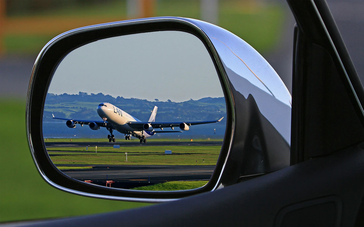 Airplane taking off viewed through car side mirror, Hurghada Airport transfer.