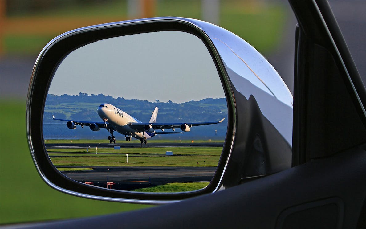 Airplane taking off viewed through car side mirror, Hurghada Airport transfer.