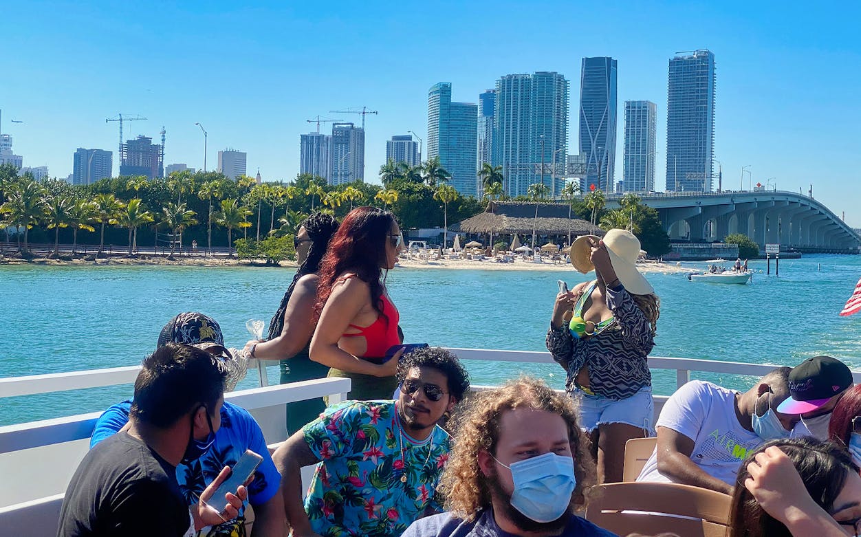 Group enjoying Miami Happy Hour Sightseeing Sunset Cruise with city skyline and bridge in background.