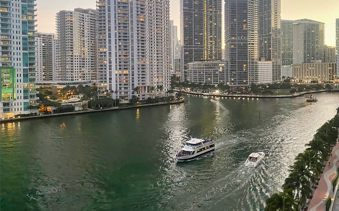 Cruise boats on Miami River at sunset with city skyline in the background.