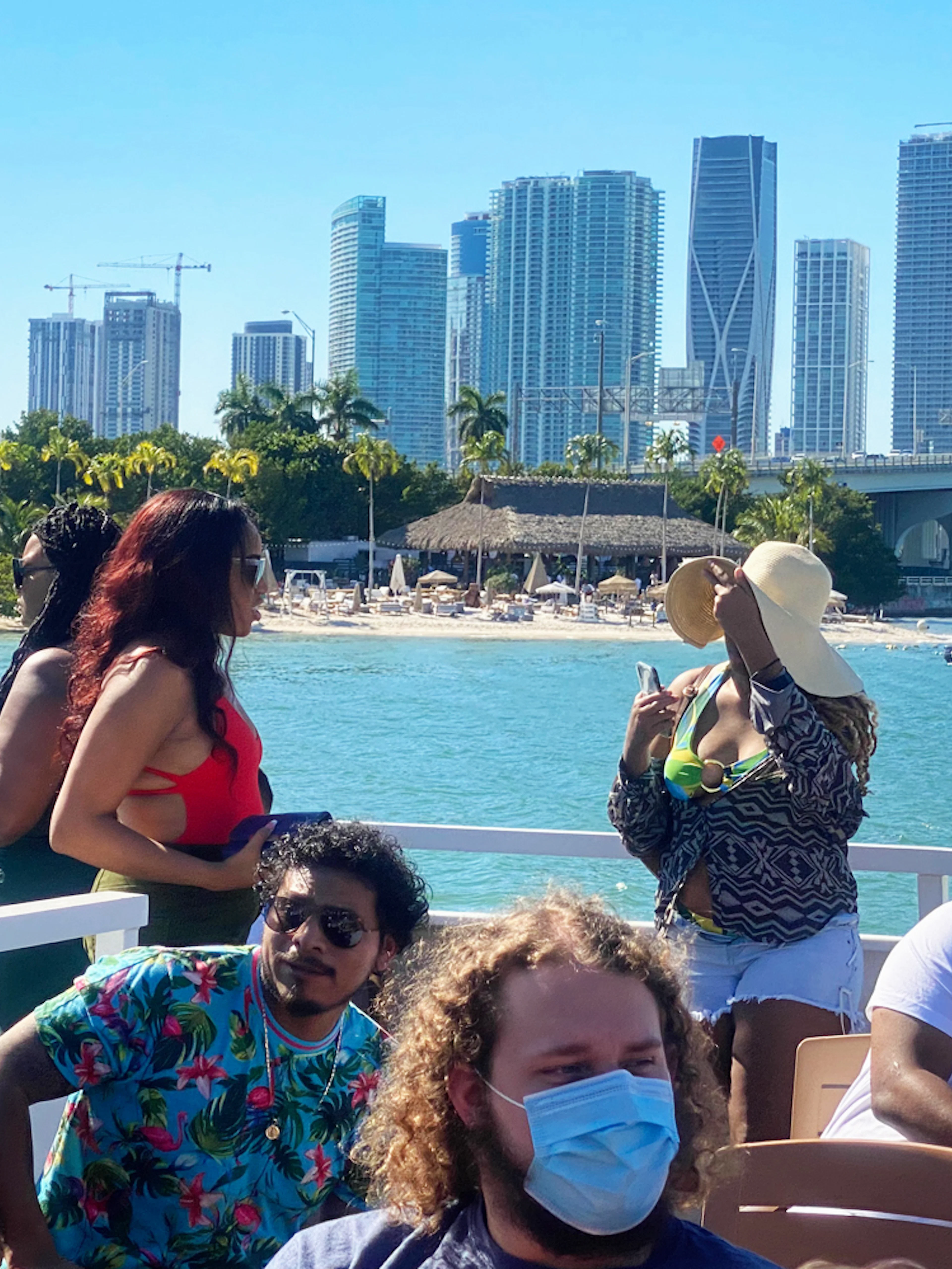 Tourists enjoying a Miami skyline cruise with cityscape and bridge in the background.