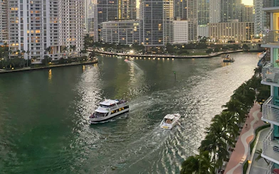 Boats cruising along the Miami River with city skyline in the background.