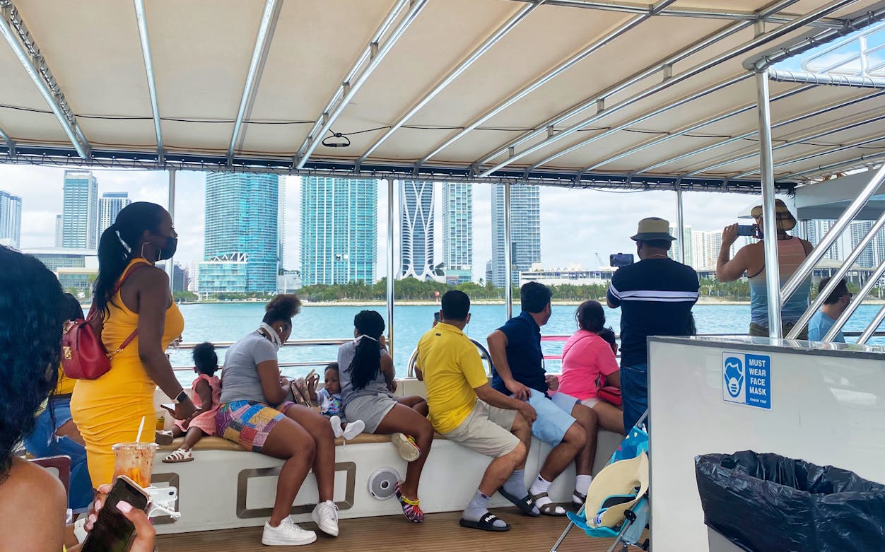 Tourists on a Miami skyline cruise boat, viewing city skyscrapers.