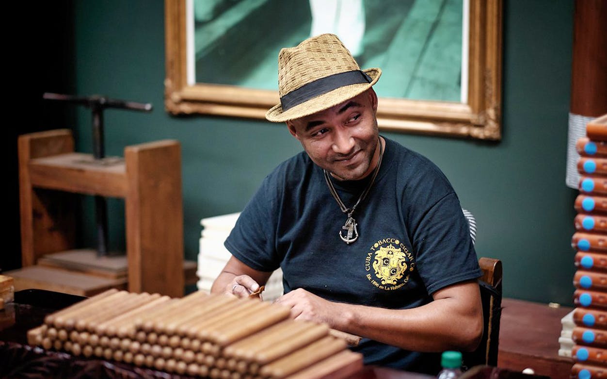 Cigar maker crafting cigars in Miami shop during movie tour and bay cruise.