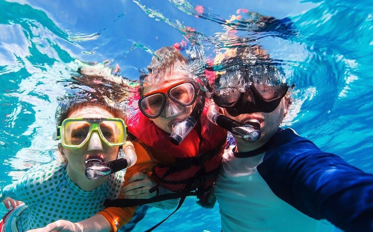 Snorkelers enjoying clear waters on Isla Mujeres catamaran tour.
