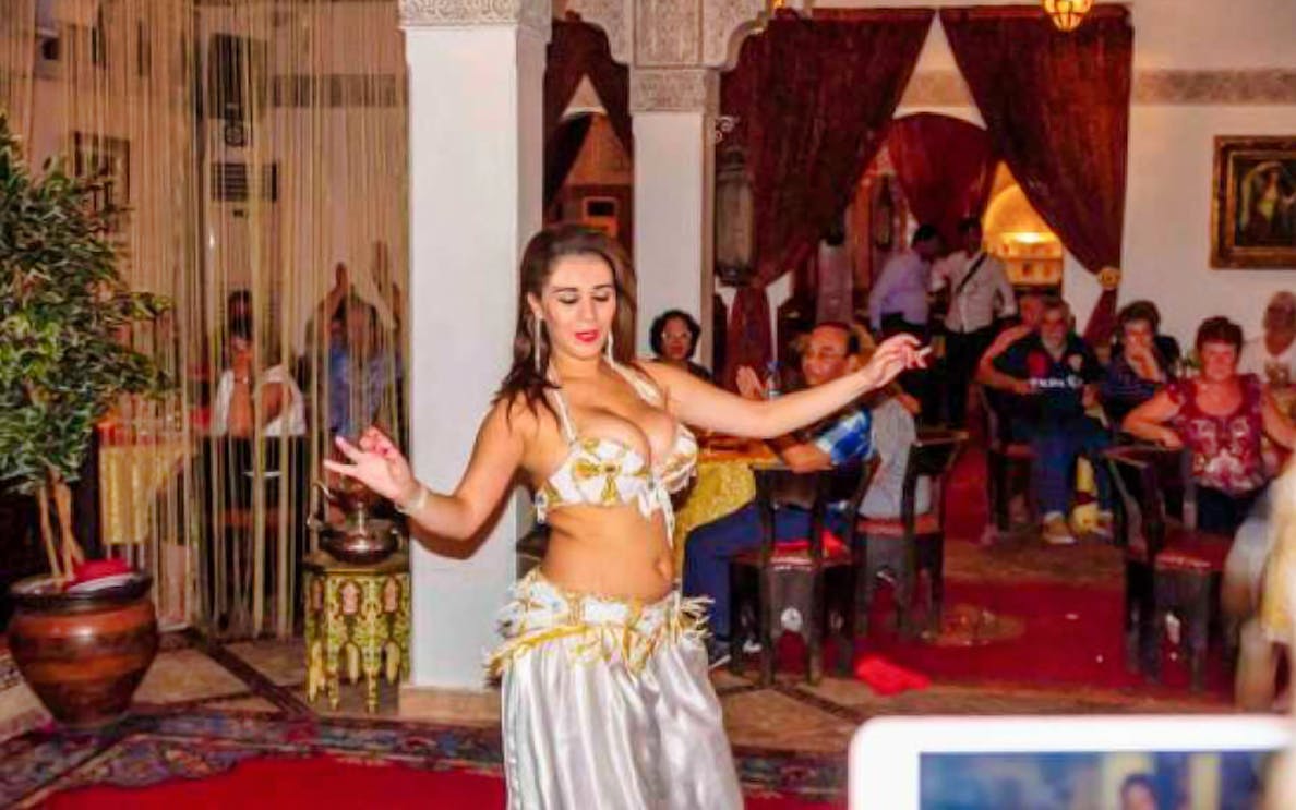 Belly dancer performing on a Nile dinner cruise with audience seated in a decorated venue.