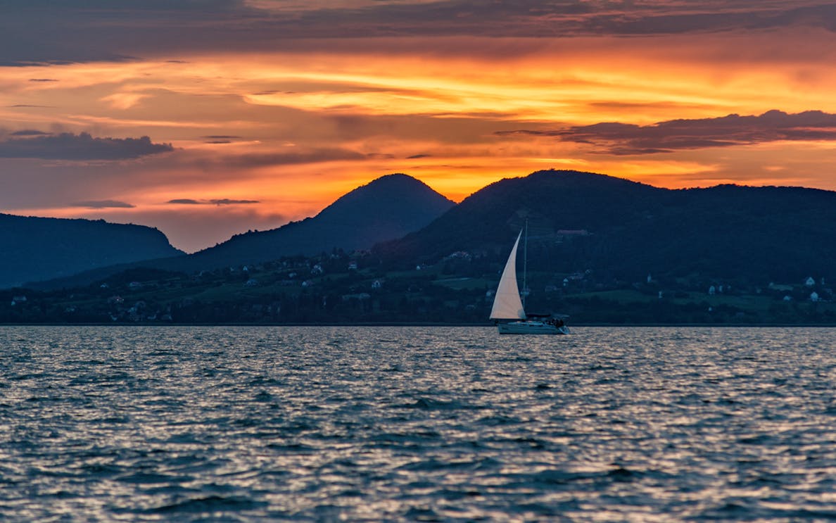 Sailboat on the Nile at sunset with mountains in the background.