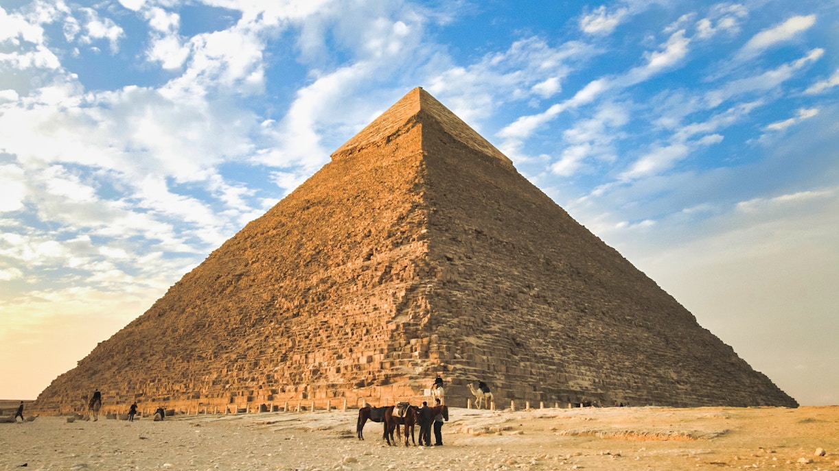 Giza Pyramid with camels in foreground under a blue sky, part of Cairo layover tour.