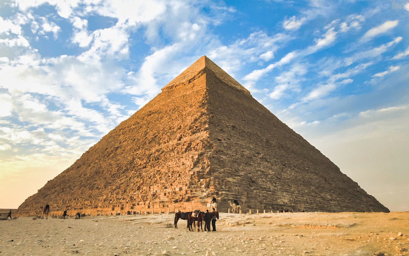Giza Pyramid with camels in foreground under a blue sky, part of Cairo layover tour.