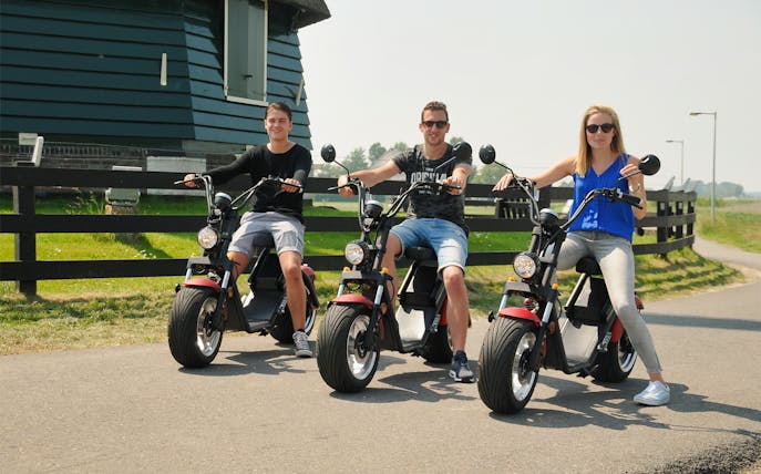 Group riding e-scooters in Volendam countryside during tour.