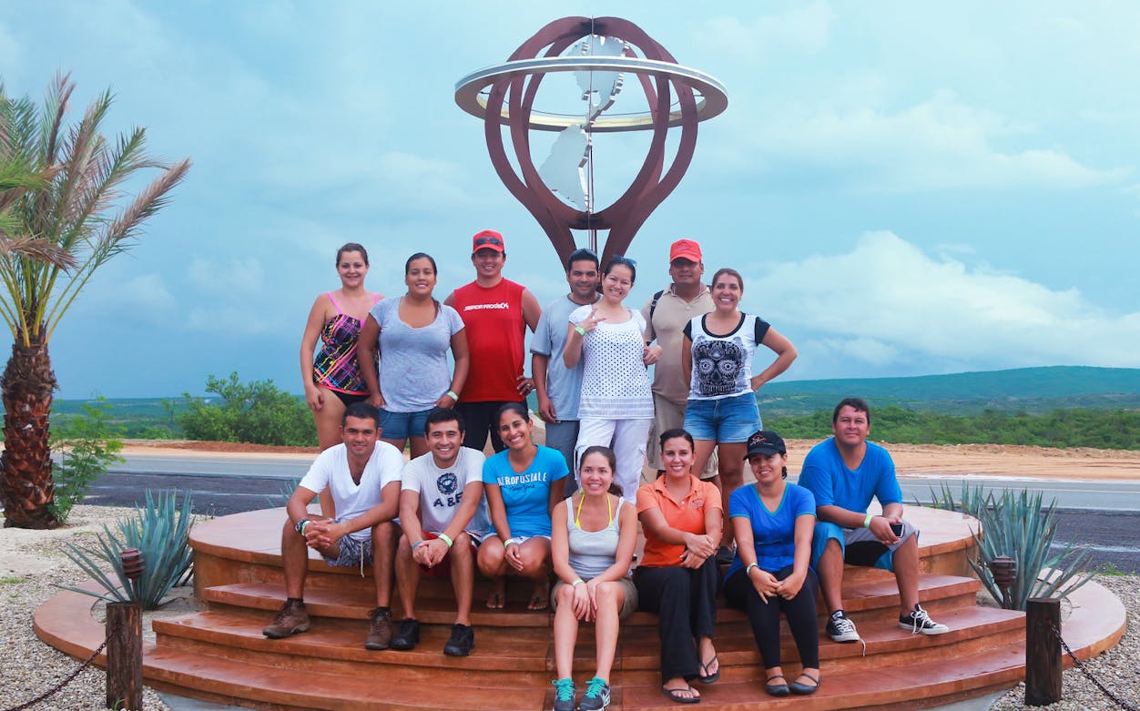 Group of tourists posing by a sculpture during Baja Jeep Offroad Private Tour.