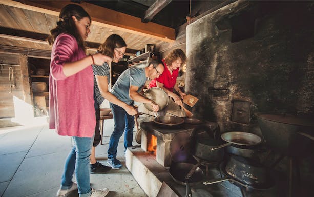 Visitors engaging in traditional cooking at Ballenberg Swiss Open-Air Museum.