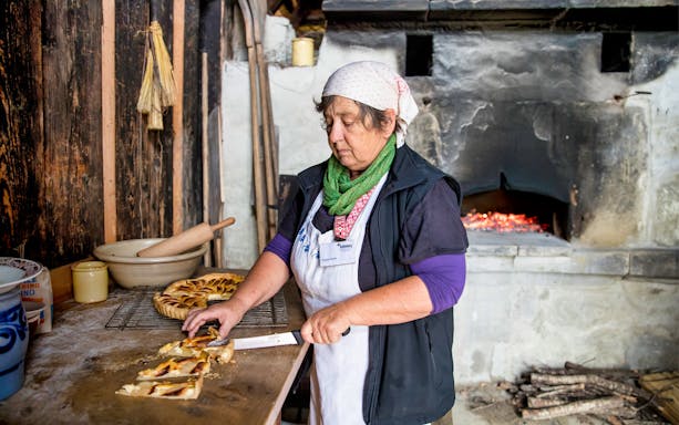Woman slicing traditional pastry at Ballenberg Swiss Open-Air Museum.