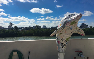 Colorful dolphin statue at Clearwater Marine Aquarium with city skyline in background.