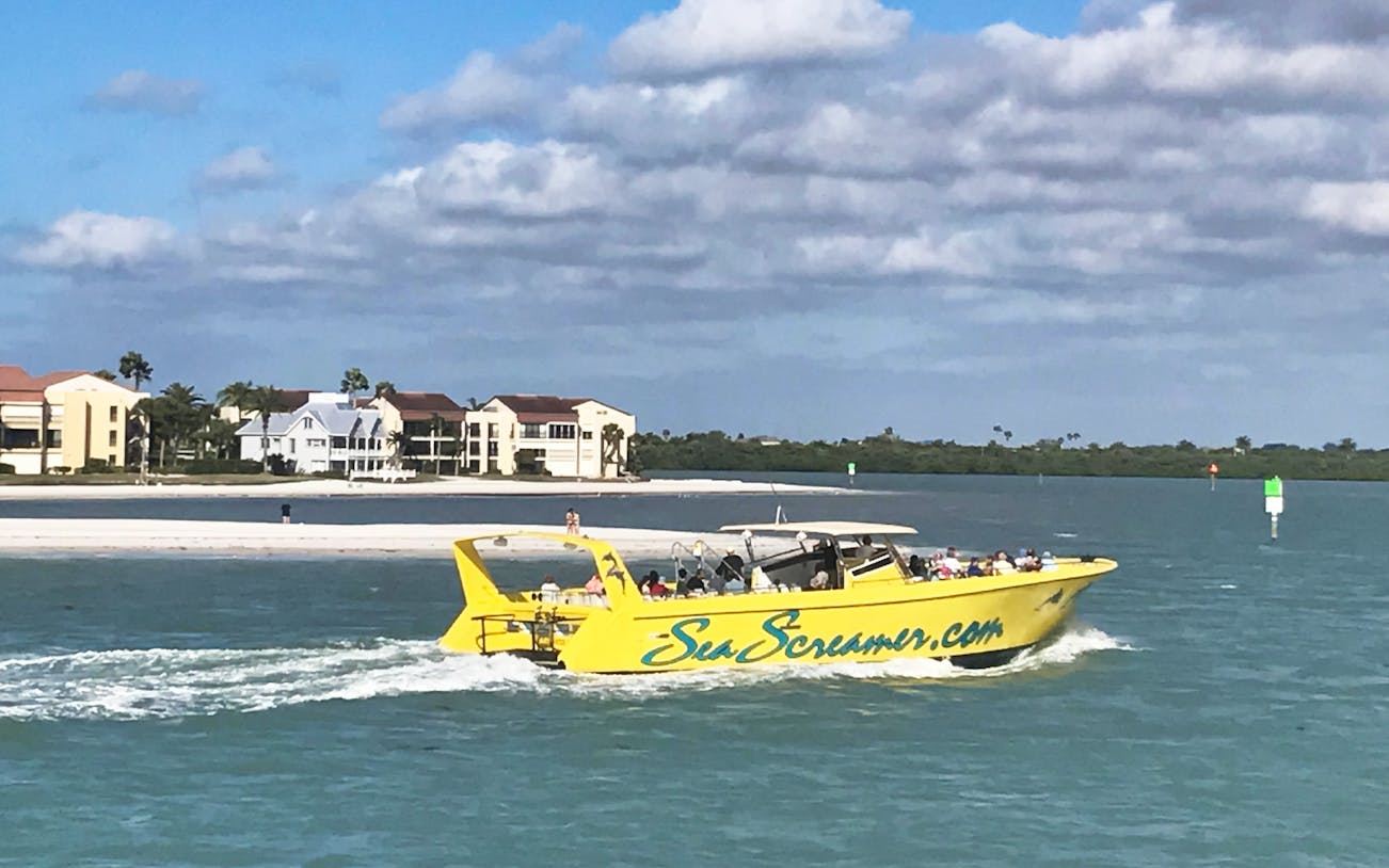 Yellow Sea Screamer boat cruising near Clearwater Beach with buildings in the background.