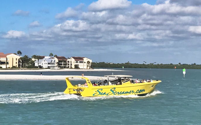 Yellow Sea Screamer boat cruising near Clearwater Beach with buildings in the background.