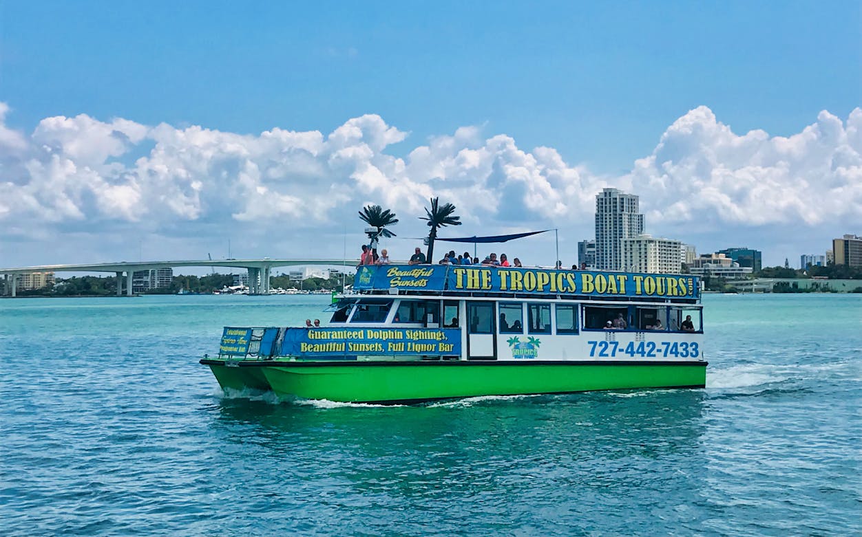 Tour boat cruising in the Gulf of Mexico with city skyline and bridge in the background.