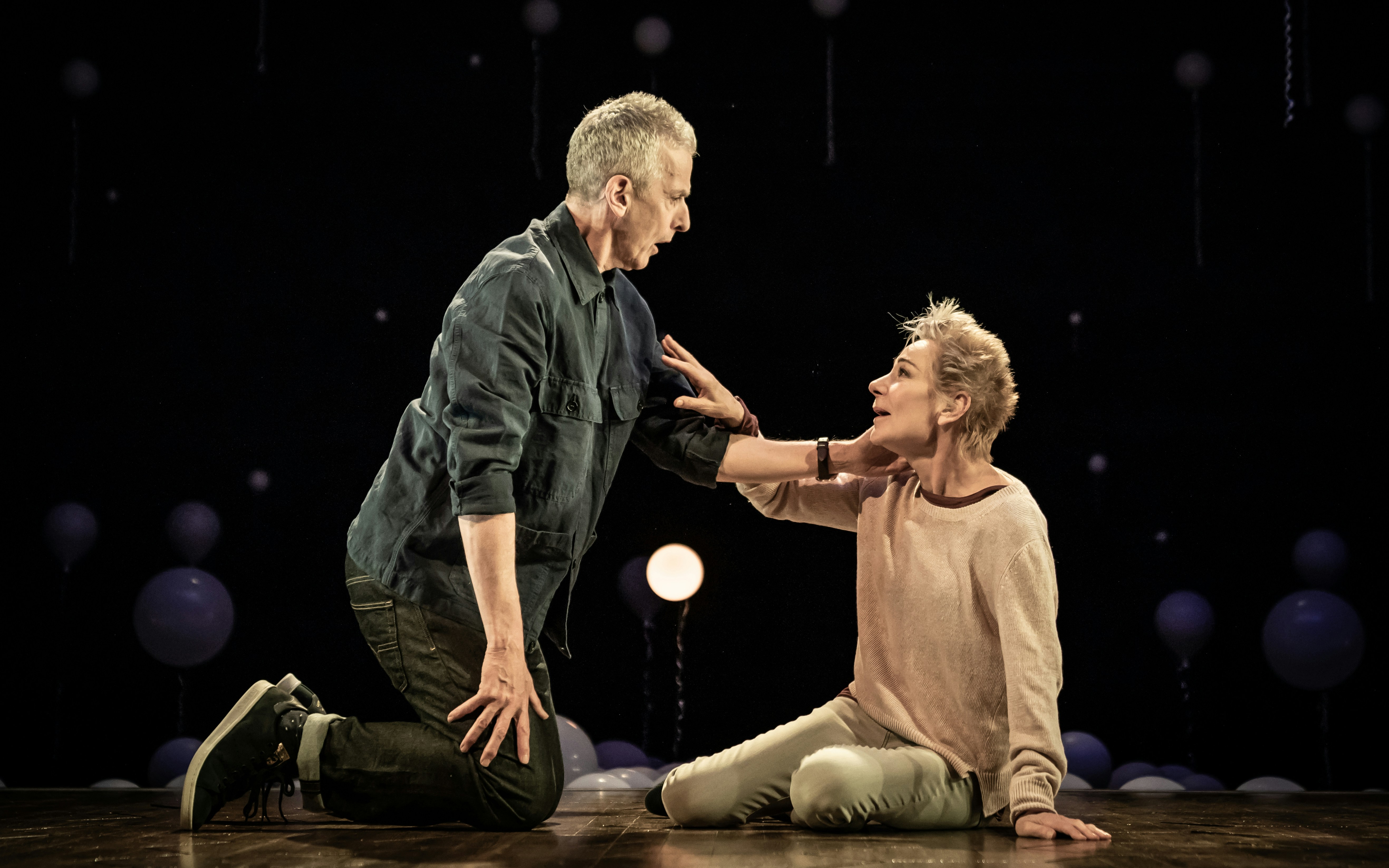 Two actors performing an emotional scene on stage in the play "Constellations.