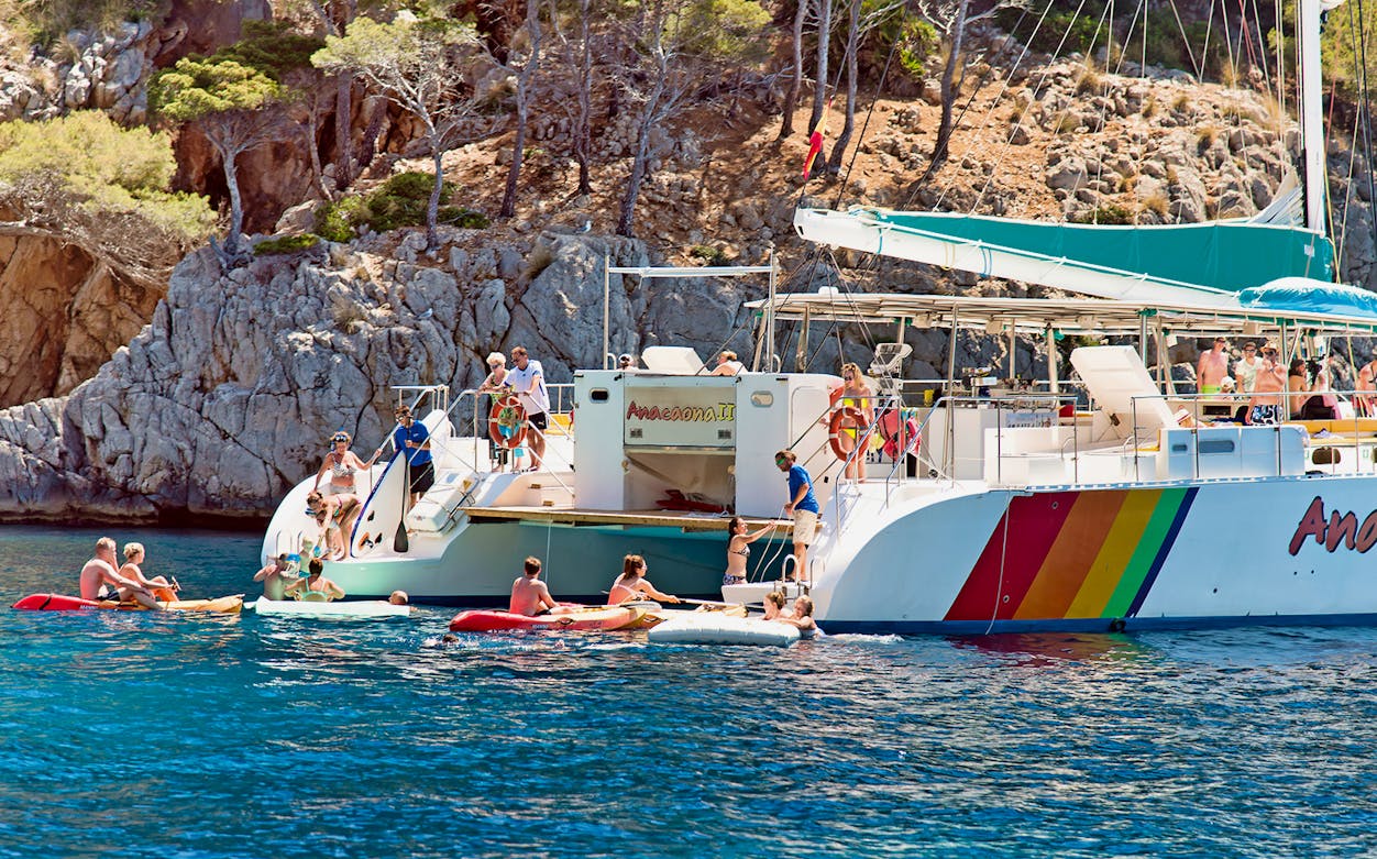 Small group enjoying a boat tour in Alcudia, Mallorca, with food and drinks on board.
