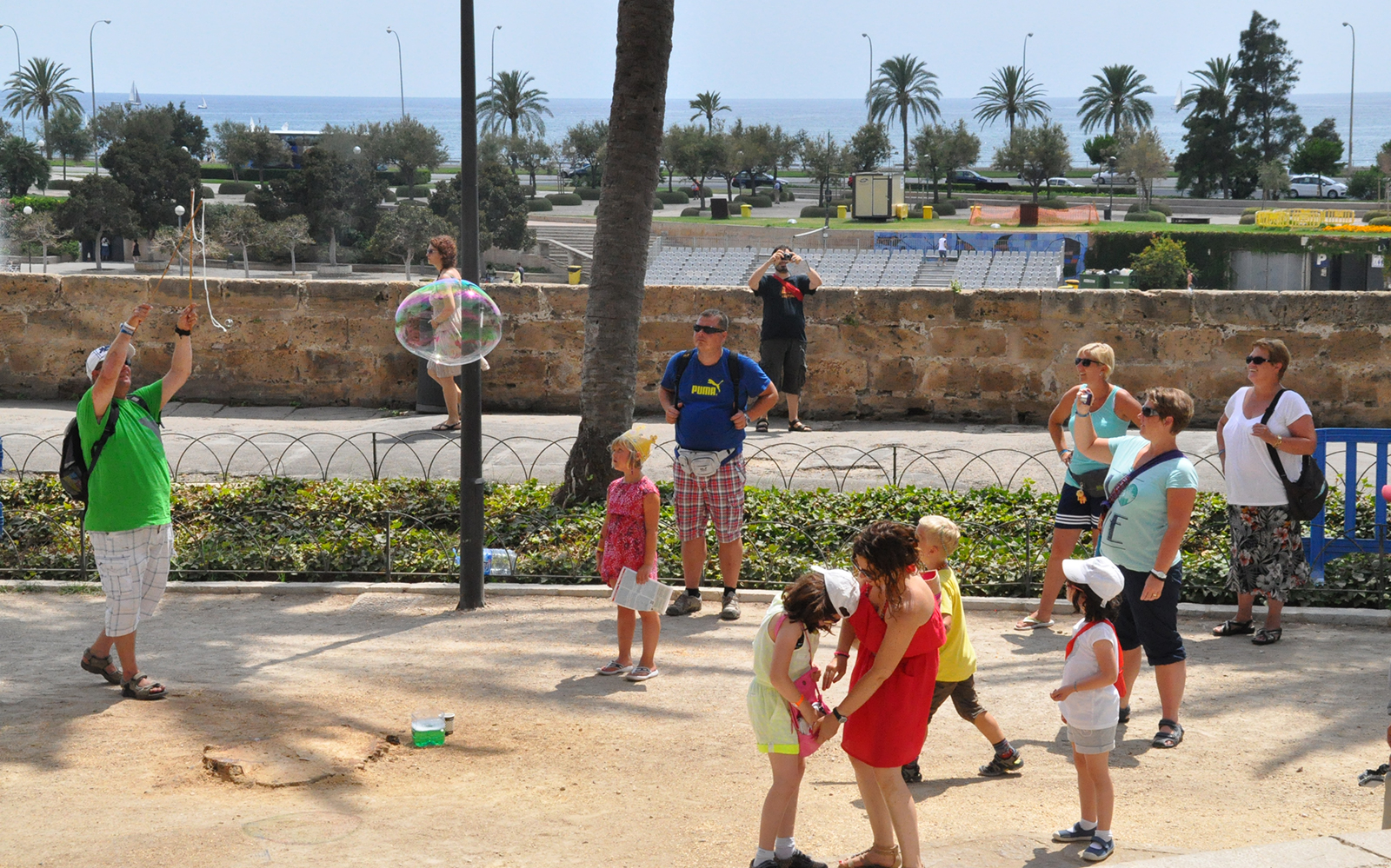 Tourists watching a street performer with bubbles near Palma Cathedral, Mallorca.