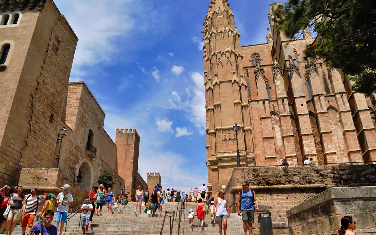 Visitors walking near Palma Cathedral on a guided tour in Palma de Mallorca.