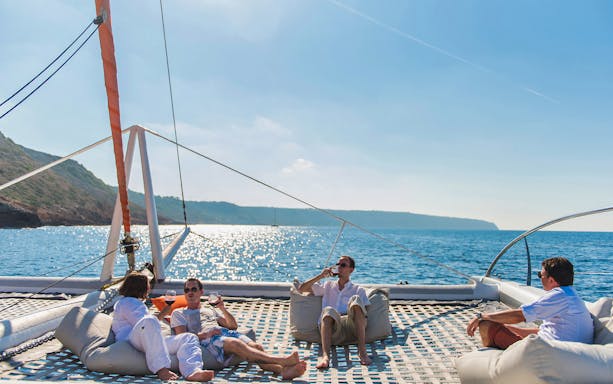 People relaxing on a catamaran during the Coll Baix Beach Boat Tour, with scenic views of Cap Formentor.