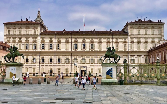 Royal Palace of Turin facade with equestrian statues and visitors in the foreground.
