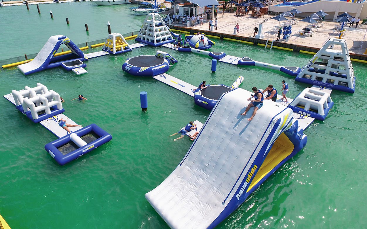 Inflatable water park with slides and obstacles at Aquabounce, people enjoying activities.