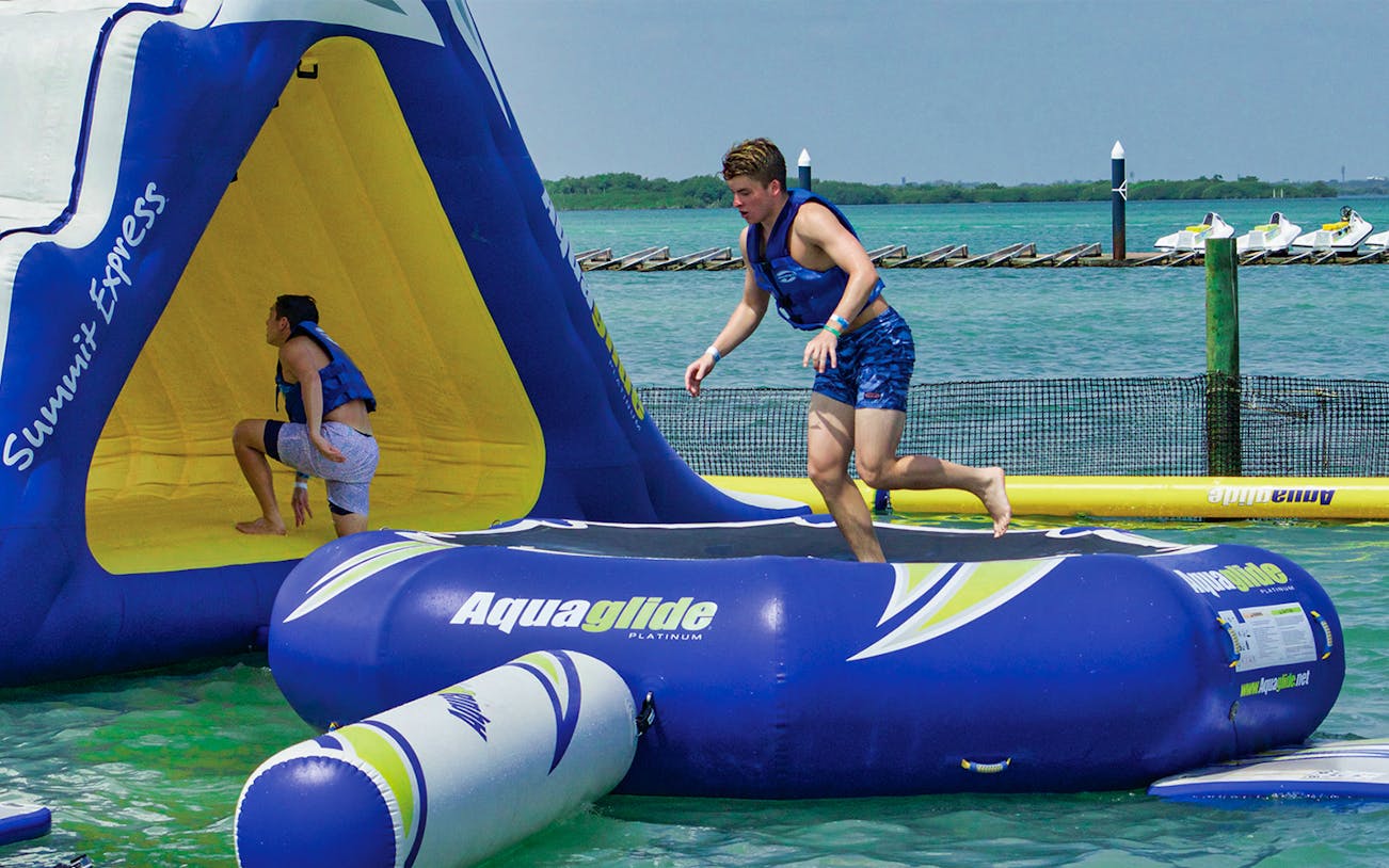 Participants enjoying Aquabounce inflatable water park activity.