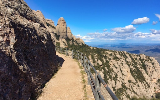 Hiking trail along rocky cliffs at Montserrat Monastery, Spain, with scenic mountain views.