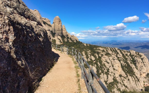 Hiking trail along rocky cliffs at Montserrat Monastery, Spain, with scenic mountain views.