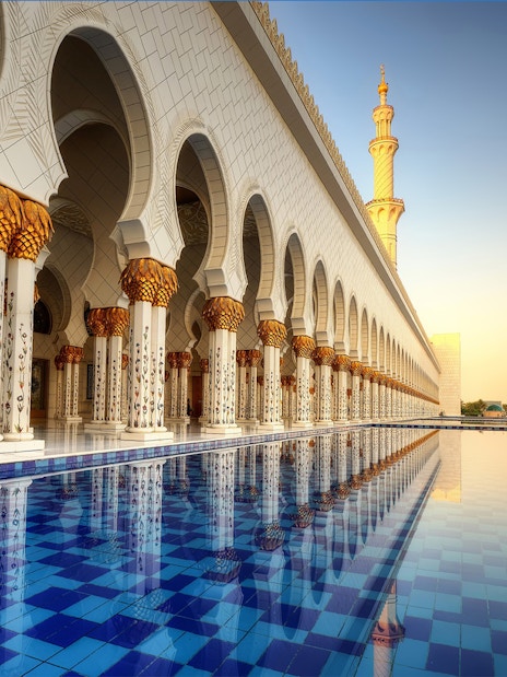 Abu Dhabi Mosque exterior with reflection in water, part of guided tour including Louvre Museum.