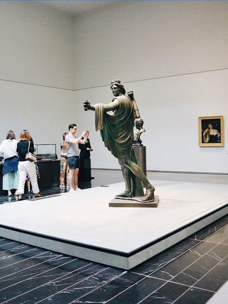Visitors viewing sculptures and paintings at Louvre Museum Abu Dhabi.