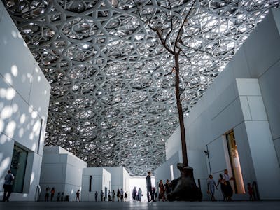 Louvre Abu Dhabi exterior with modern architecture and reflective water in Abu Dhabi