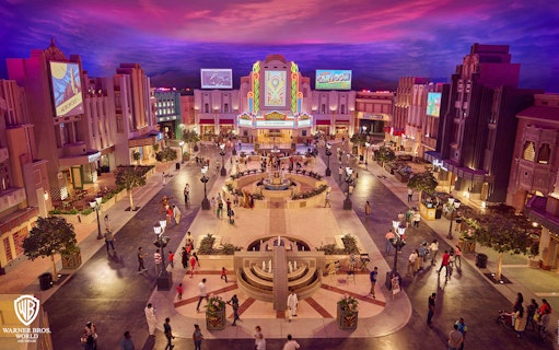 Warner Bros. World Abu Dhabi plaza with visitors exploring themed buildings.