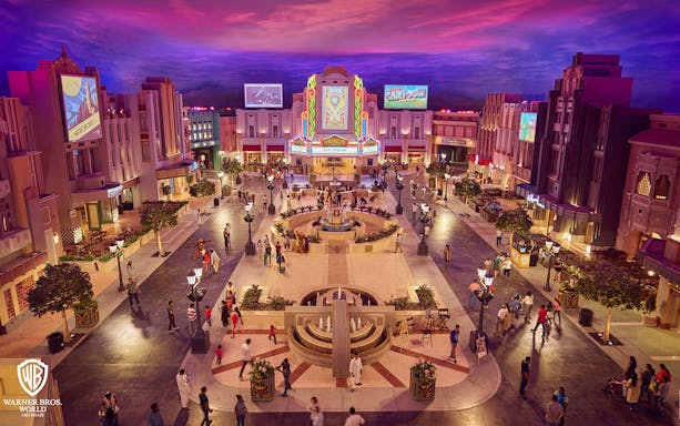 Warner Bros. World Abu Dhabi plaza with visitors exploring themed buildings.