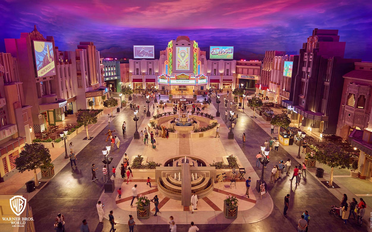 Warner Bros. World Abu Dhabi plaza with art deco buildings and visitors exploring.