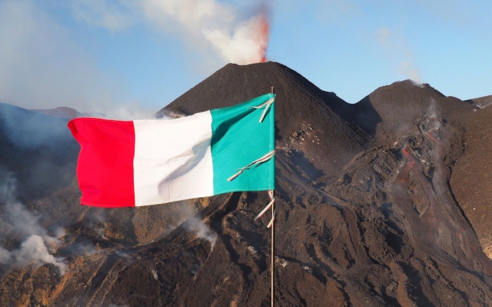 Italian flag waving in front of Mount Etna with smoke, Sicily, Italy.