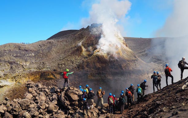 Group of tourists exploring Mount Etna's volcanic landscape in Sicily.