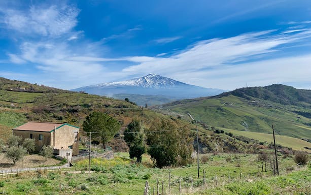 Mount Etna with green hills and a rustic house in Etna Park, Sicily.